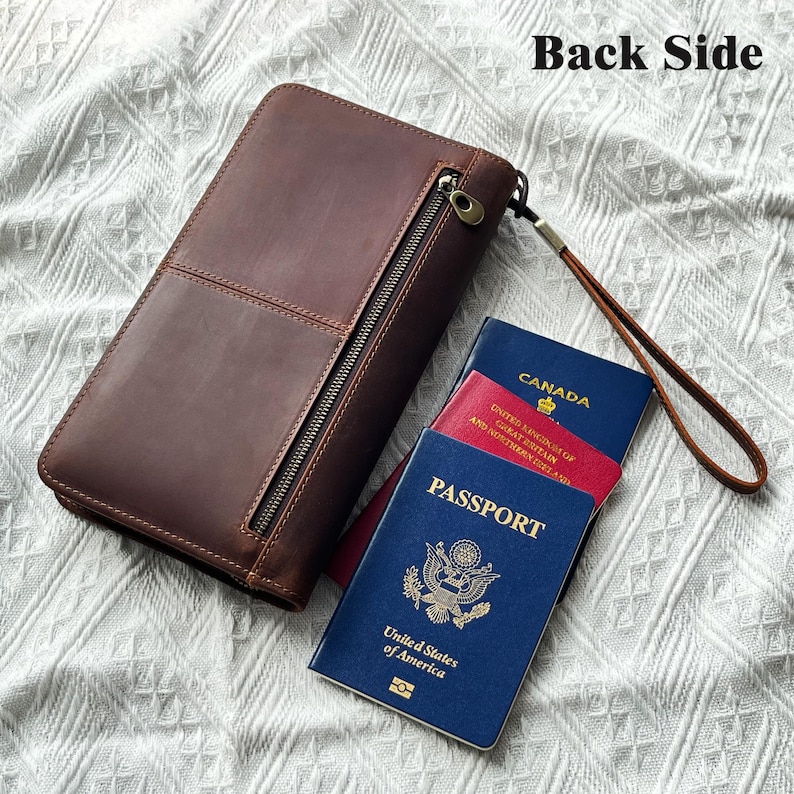 May include: A brown leather wallet with a zipper closure and a wrist strap. The wallet is next to three passports: a blue United States passport, a red United Kingdom passport, and a blue Canadian passport.