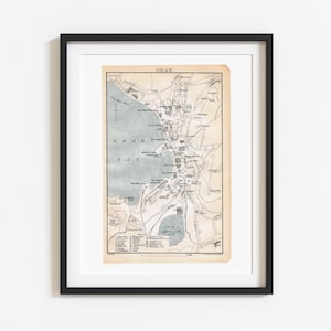 May include: A framed vintage map of Oban, Scotland, featuring a beige background with black ink lines detailing streets, buildings, and Oban Bay. The map includes a legend at the bottom, a compass rose, and the text OBAN at the top centre.