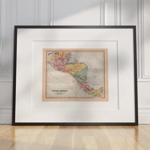 May include: Framed vintage map of Central America, showing a detailed depiction of the region with various colours highlighting different areas. The map is set within a white mount and a black frame, suitable for home decor.