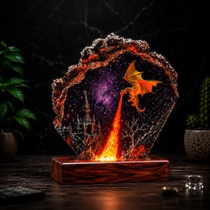 Pode incluir: Uma luminária decorativa de resina com uma moldura irregular tipo geodo e um fundo de nebulosa roxo escuro. No interior, um castelo em miniatura ergue-se perto de uma árvore nua, enquanto um dragão amarelo expele um jato de fogo laranja vivo.