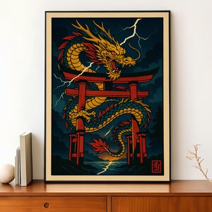 Op de afbeelding: Een ingelijste kunstdruk met een gestileerde illustratie van een gouden draak met rode accenten, bovenop een rode torii-poort. De draak staat tegen een donkerblauwe lucht met bliksem, over een landschap met water en een zonsondergang.