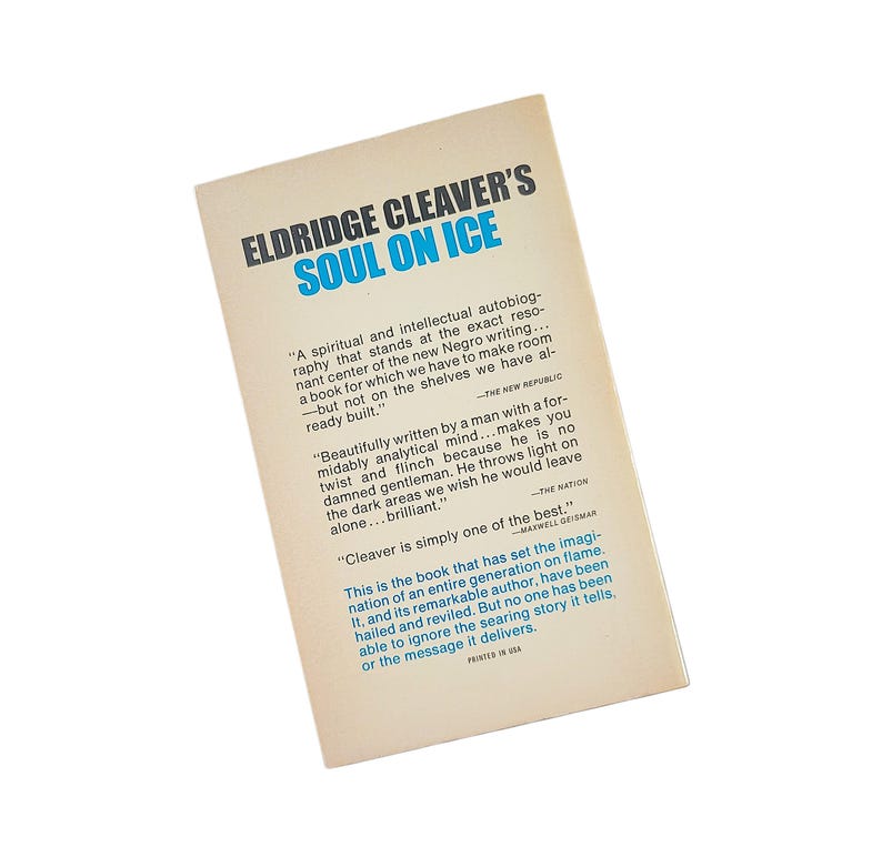 May include: The back cover of the book "Soul on Ice" by Eldridge Cleaver. The title is in blue, with the author's name above it. The cover has quotes and text in black. The book is on a white background.