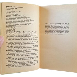 May include: Open book pages with text, including copyright information and acknowledgments. The left page lists book titles and authors, while the right page contains a thank you note. The book is held by a hand.
