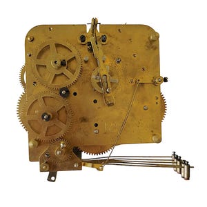 May include: Close-up of a vintage clock movement with brass gears and components. The mechanism features multiple interlocking gears, levers, and a pendulum weight system. The brass components have a warm, aged patina, suggesting the clock's age and history.
