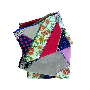 Peut inclure: Une pochette en tissu patchwork avec une variété de motifs et de couleurs. La pochette présente des motifs floraux, à pois et géométriques dans des tons de rouge, bleu, vert et beige. Les bords sont cousus avec du fil contrastant.