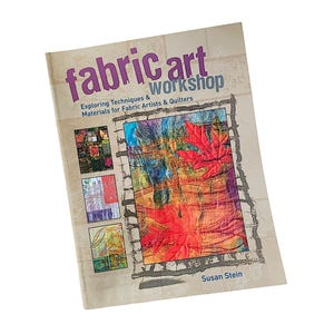 May include: A softcover book titled Fabric Art Workshop: Exploring Techniques & Materials for Fabric Artists & Quilters by Susan Stein. The cover features a large central image of red maple leaves on a textured background and three smaller inset images.
