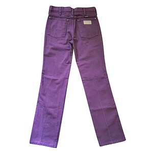 Puede incluir: Unos pantalones vaqueros de color morado con dise&ntilde;o de cintura alta, trabillas para cintur&oacute;n, dos bolsillos traseros y remaches met&aacute;licos plateados. Una etiqueta rectangular blanca de la marca est&aacute; cosida en el bolsillo trasero derecho.