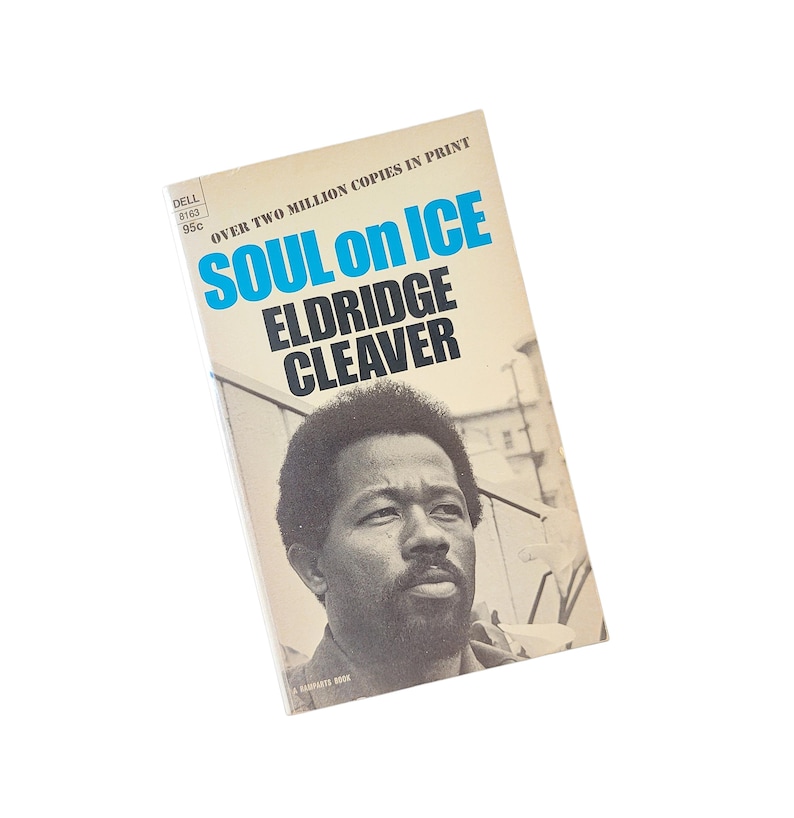 May include: Vintage paperback book titled "Soul on Ice" by Eldridge Cleaver. The cover features a black and white portrait of the author and the title in blue and black text. The book is a Dell paperback.
