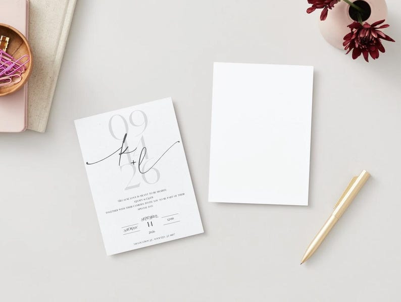 May include: A white wedding invitation with a gray and black design. The invitation features the date "09.26" and the initials "K+L" in a script font. The text on the invitation reads "We are so excited to invite you to celebrate with us as we say "I do"."