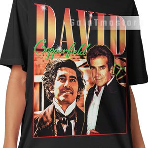 May include: Black t-shirt featuring a graphic of David Copperfield with the text "DAVID Copperfield" in a retro style. The shirt has a red border around the image and a GoldTmastore logo.