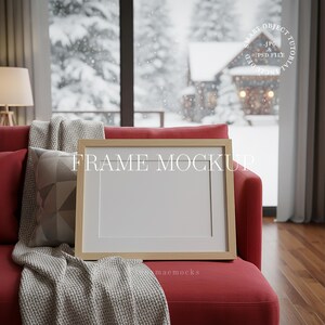 May include: A rectangular frame mockup with a light wood finish, resting on a red sofa. The frame has a white mat and a blank white space for an image or artwork. A gray throw blanket and a patterned pillow are also on the sofa. The text "FRAME MOCKUP" is visible.