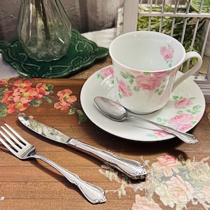 May include: A handmade wooden sign with the text "Welcome" in a whimsical font. The sign is painted white with a distressed finish, and features a decorative floral design in shades of pink and green. It measures approximately 12 inches wide.