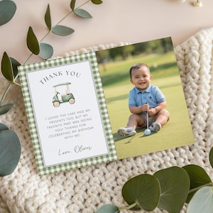 Könnte beinhalten: Eine Dankeskarte zum Thema Golf mit einem Foto eines lächelnden Babys auf einem Golfplatz. Die Karte hat einen grün-weiß karierten Rand und den Text "THANK YOU" sowie eine Geburtstagsbotschaft.