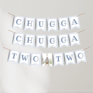 May include: A banner set for a second birthday celebration. The banner spells out "CHUGGA CHUGGA TWO TWO" in blue letters on white pennants with blue stripes. A small picture is in the center.