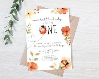 May include: A white invitation card with floral and ladybug illustrations, announcing a first birthday. The text reads "our little lady is turning ONE" with the date July 23rd and time 2 PM.