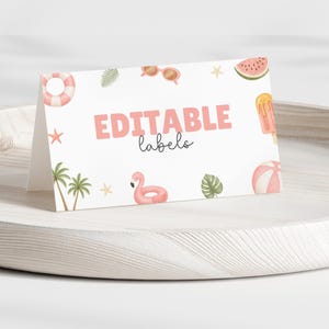 May include: A white card with the words "EDITABLE labels" in pink, featuring watercolor illustrations of summer items like a flamingo, sunglasses, and watermelon. The card is displayed on a light wooden tray.
