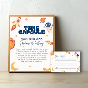 May include: A white card with a blue and white space-themed design. The card says "Time Capsule" and "Sealed until 20XX Payton's 18th birthday". There is a smaller card that says "Dear Payton" with lines for writing.