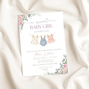 May include: A baby shower invitation with the text "a sweet BABY GIRL is on her way!" features watercolor illustrations of baby clothes hanging on a clothesline. Floral accents and event details are included.
