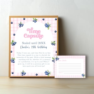 Könnte beinhalten: Eine Karte mit rosa und weißem Karomuster und einem blauen und weißen Heidelbeerdesign. Die Karte trägt die Aufschrift "Time Capsule" und "Sealed until 20XX Charlie's 18th birthday". Die Karte enthält auch eine Nachricht, in der man gebeten wird, eine Erinnerung oder eine Vorhersage für den Geburtstagskind zu schreiben, die er an seinem 18. Geburtstag öffnen kann.