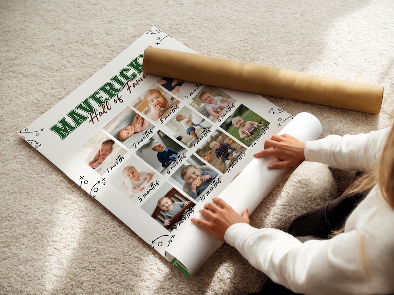 May include: A personalized baby milestone poster with the text "MAVERICK Hall of Fame" in green and white. The poster features a grid of baby photos, each labeled with a month. A rolled-up poster and a brown tube are also visible.