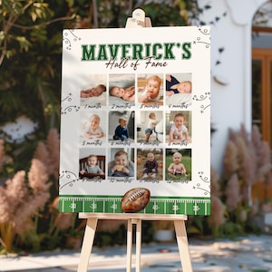 May include: A white sign on an easel with the text "MAVERICK'S Hall of Fame" in green. The sign displays 12 baby photos, each labeled with a month. A football sits at the bottom of the sign.