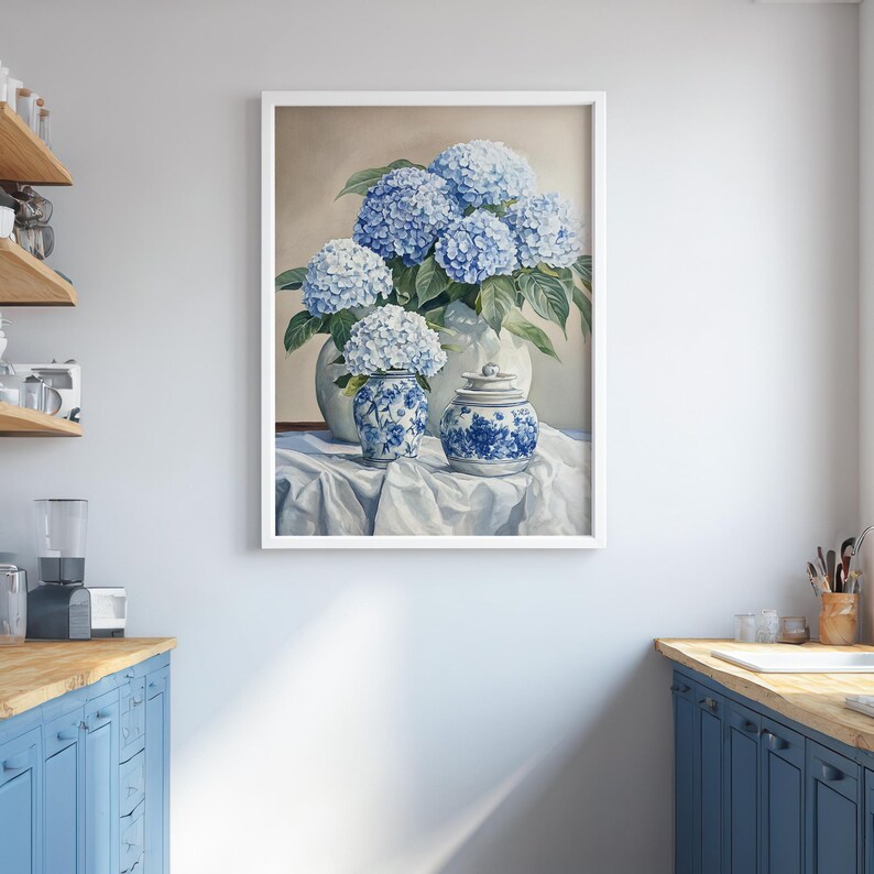 Framed hydrangea flower art hung between blue kitchen cabinets in bright modern space. Wall decoration print highlighting blue hydrangea painting as a new home gift idea.