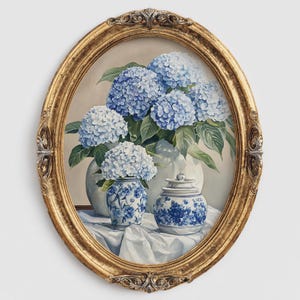 Oval gold framed hydrangea painting featuring blue and white blooms in ceramic vases on draped fabric. Blue hydrangea flower painting in vintage floral style, designed as French farmhouse wall decoration.
