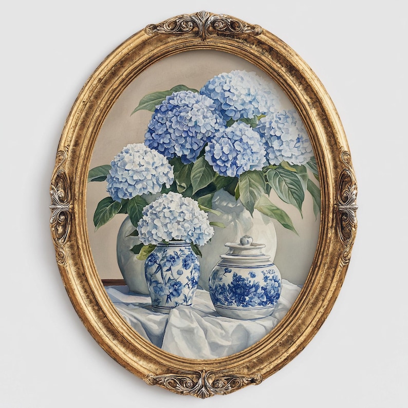 Oval gold framed hydrangea painting featuring blue and white blooms in ceramic vases on draped fabric. Blue hydrangea flower painting in vintage floral style, designed as French farmhouse wall decoration.