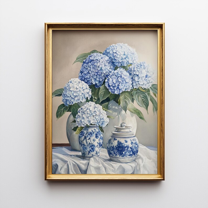 Gold framed hydrangea painting with blue blooms in porcelain jars with chinoiserie pattern against neutral background. Styled for Grandmillennial art aesthetic. New home gift idea art featuring elegant blue hydrangea floral illustration.