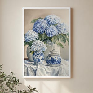 Framed hydrangea floral print on neutral wall, blue and white flower arrangement in classic ginger jars with chinoiserie. Vintage floral print featuring soft blue hydrangea blooms in cottagecore decor style.