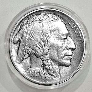 May include: A silver coin from 1915, featuring a Native American profile with the word "LIBERTY" visible. The coin is encased in a clear protective holder.