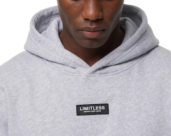 May include: A light gray hoodie with a drawstring hood and a small black rectangular patch on the chest. The patch reads "LIMITLESS NEVER LOOK BACK" in white text. The model is wearing the hoodie.