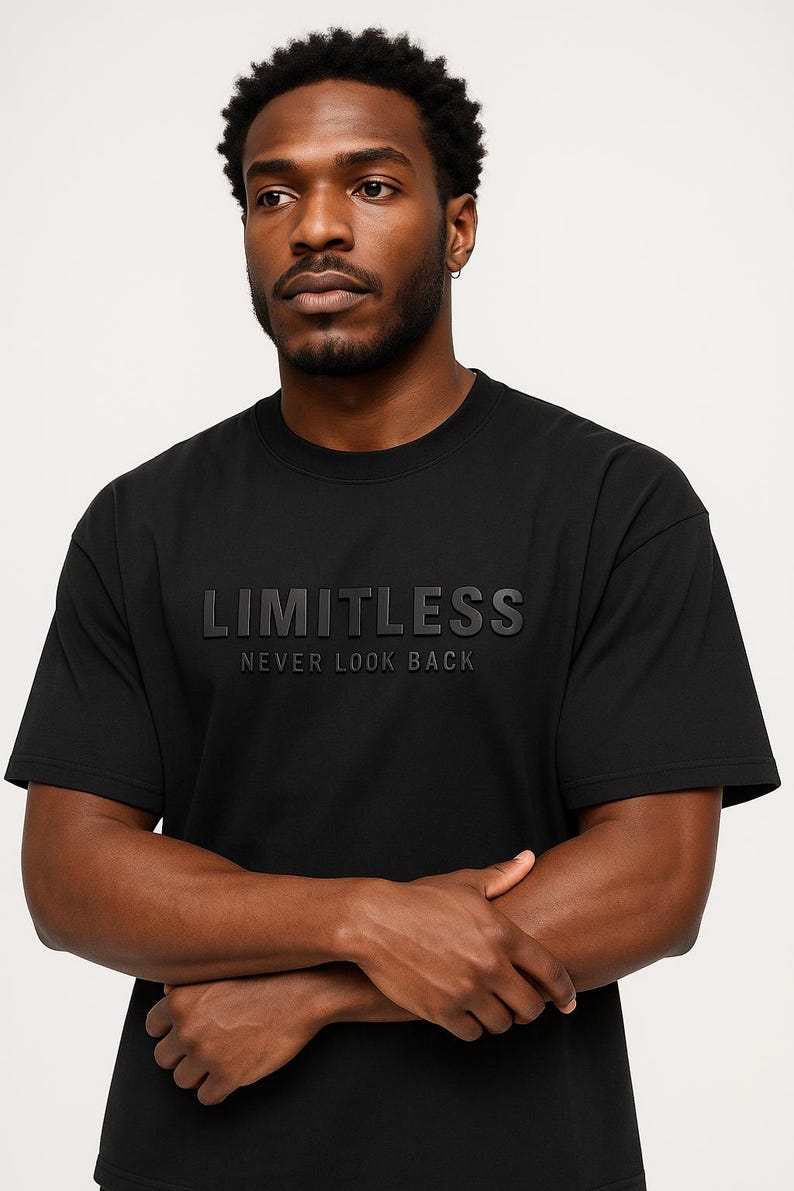 May include: Black crew neck t-shirt with the word "LIMITLESS" embossed across the chest, with the phrase "NEVER LOOK BACK" below. The shirt is a solid black color and has short sleeves.