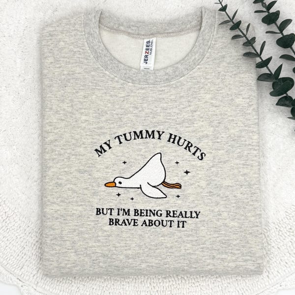Sudadera con bordado de pato: cuello redondo y divertida con la frase "Me duele la barriga"