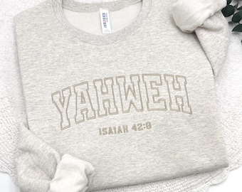 May include: A light gray sweatshirt with the word "YAHWEH" in a tan, collegiate-style font. Below the word is the text "ISAIAH 42:8". The sweatshirt has a crew neck and long sleeves.