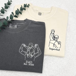 a couple of t - shirts sitting on top of a white towel