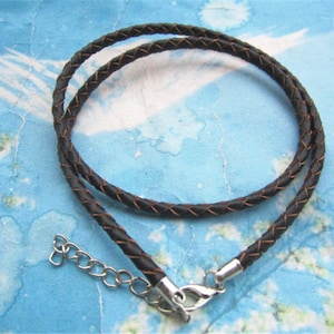 May include: A black leather cord necklace with a silver clasp. The cord is braided and has a subtle sheen.