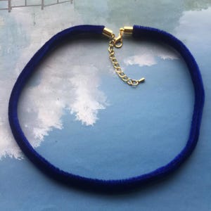 May include: A blue velvet choker necklace with a gold chain extender.