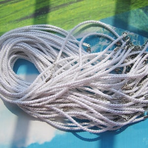 May include: A pile of white cord necklaces with silver clasps. The cords are twisted and piled on top of each other.