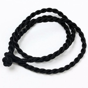 May include: A black braided cord with a knot at one end. The cord is approximately 1/2 inch thick and is made of a soft, pliable material.