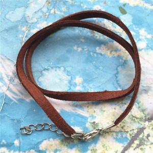 May include: A brown suede cord necklace with a silver clasp and chain.