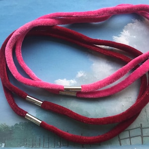 May include: Two velvet cords, one pink and one burgundy, with silver magnetic clasps. The cords are layered on top of each other.