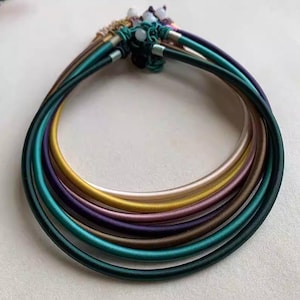 May include: A set of three ceramic mugs with a speckled, matte finish. The mugs are in shades of cream, light gray, and dark gray. Each mug has a simple, minimalist design and a rounded handle.