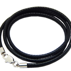 Puede incluir: Un collar de cordón de cuero negro con cierre y tapas de extremo plateadas.