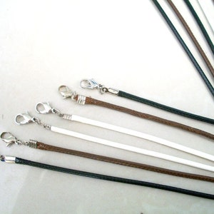 May include: Assortment of leather cords with silver clasps in black, brown, and white.