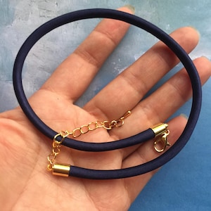 May include: A navy blue choker necklace with a gold chain and clasp. The necklace is made of a soft, flexible material.