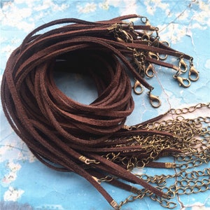 May include: A pile of brown suede cords with gold-toned lobster clasps. The cords are approximately 18 inches long and are perfect for making necklaces, bracelets, or other jewelry.