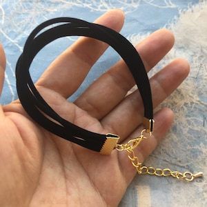 May include: A black velvet choker necklace with a gold clasp and extender chain.