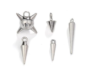 May include: A collection of silver-colored metal charms in various shapes. The charms include a spiky ball, two cone-shaped charms, and two elongated spike charms. Each charm has a small loop for attaching to jewelry or other crafts.