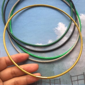 May include: Four different coloured metal cable chains, including gold, silver, green, and black. The chains are arranged in a circle, with the gold chain on top.